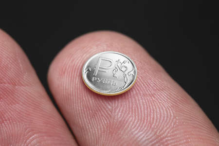 Coin of one Russian ruble of miniature size on a fingertip - the concept of inflation of the Russian...