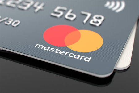 Credit card Mastercard on a black shiny surface. Logo of the payment system Mastercard close-up....