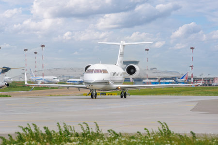 A private white Bombardier Challenger 600 business jet on the taxiway of Vnukovo Airport is preparing for takeoff. Jet business aviation. Moscow, Russia - July 2, 2014のeditorial素材