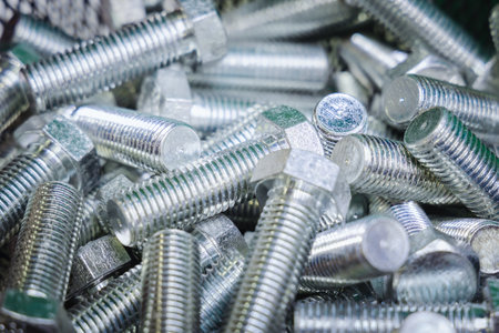 Stainless steel bolts, close-up. A pile of silver bolts. Fasteners made of steel. Construction...
