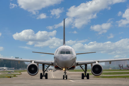 Close-up of a passenger plane on the taxiway at the airport against the backdrop of a beautiful cloudy sky, front view. A jet plane is preparing to take offの写真素材