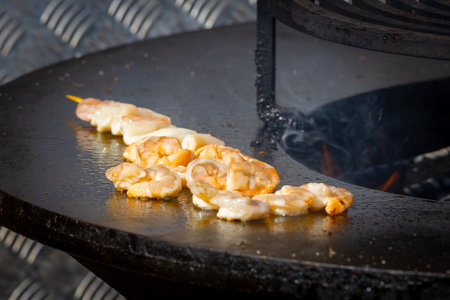 Grilling seafood. Shrimps and squids are cooked on wooden skewers over an open fire. Sea delicacies. Street foodの写真素材