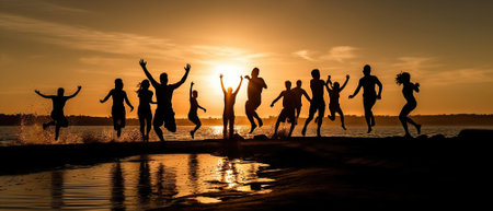 Silhouettes of a group of people on the beach, joyfully jumping up against the backdrop of the setting sun. The scene is filled with a feeling of freedom and happinessの素材