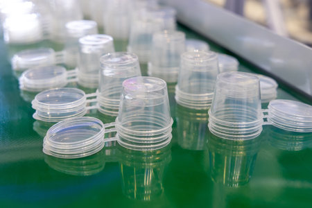 Production of plastic products from PP polypropylene. Conveyor belt with rows of round transparent...
