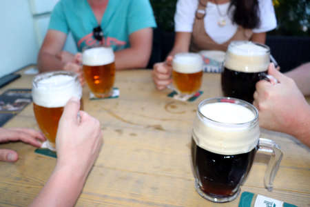 Hands holding glasses with beer on a table