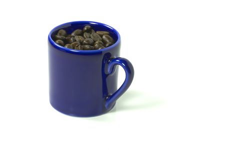 A clue mug full of coffee beans isolated on whiteの写真素材