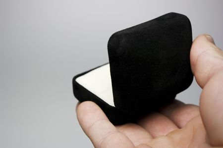 Hand presenting an open black ring box.