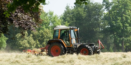 tractor with hay turning equipment on the meadowの写真素材