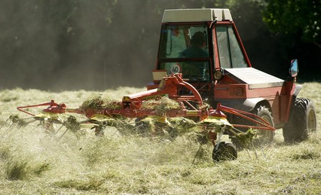 little tractor with hay turning equipment on the meadow