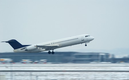 airplane over snowy runway taking offの写真素材