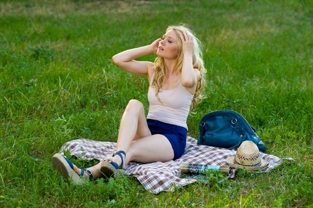 young blond on a blanket in the green parkの写真素材
