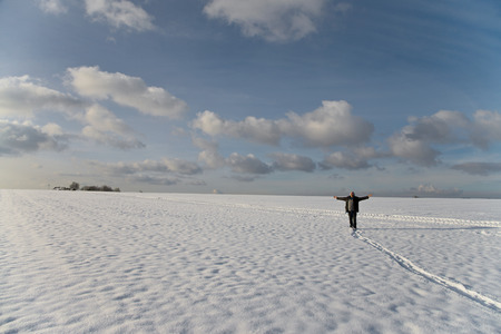 a man standing on a bright snowy high plateau with wide outstretched arms looking to heavenの写真素材