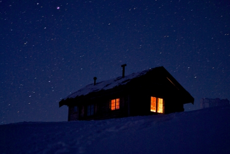 Cozy cabin on cold winter night  Long exposure shows stars and light from the candles inside the cabinのeditorial素材
