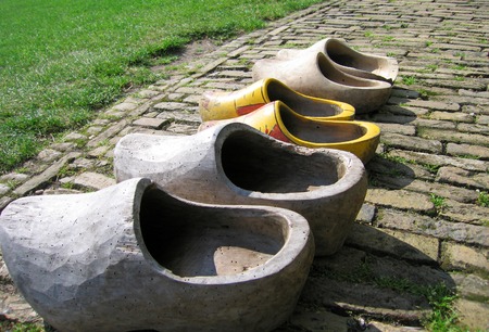 Real original and traditional wooden shoes (some with woodworm) on a brick road