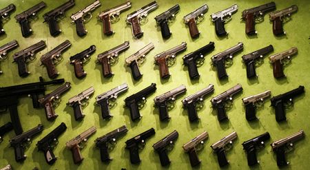 All kinds of different handguns displayed on green background for sale 