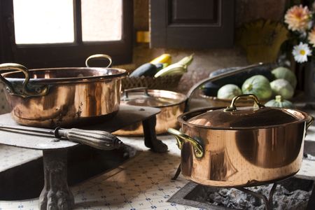 Copper pans on 17th century coal stove in preserved kitchen in an old chateau in Burgundy, France. Still life with fruit and natural light.の写真素材
