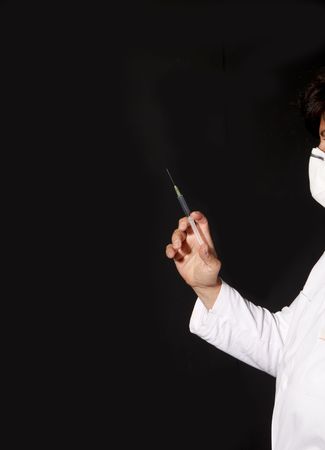 Female doctor with surgical mask and white coat with syringe in handの写真素材