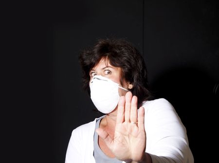 Woman with surgical mask holding up hand to keep the swine flu awayの写真素材