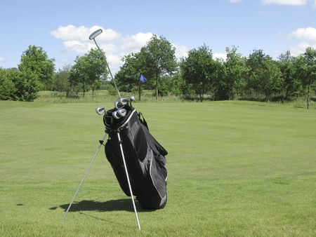 Golfbag with irons and putter sticking out near golf greenの写真素材