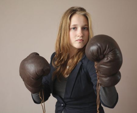 Pretty young girl with boxing gloves  looking powerful and standing tallの写真素材