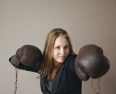 Pretty young woman with boxing gloves giving a punch. Focus on face.の写真素材