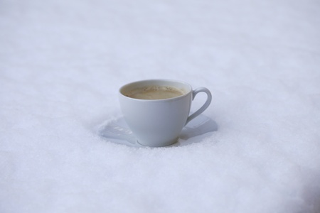 Hot cup of coffee in the cold snowの写真素材