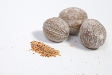 Three nutmegs and nutmeg powder on a white backgroundの写真素材