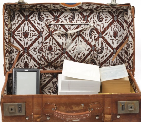Suitcase with big stacks of books and one small e-book