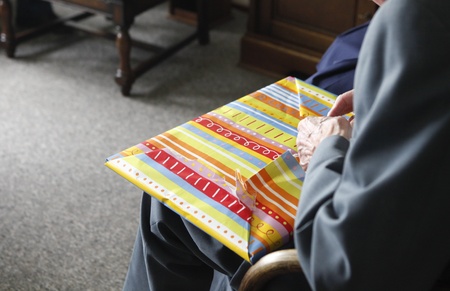 Old man unwrapping present at home