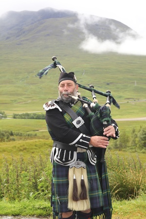 SCOTLAND-JULY, 16TH: Scotsman playing bagpipes on the road in the Highlands on July 16,2011のeditorial素材