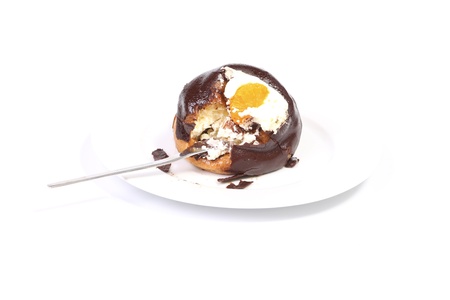 Bire of chocolate covered profiterole with whipped cream on a fork