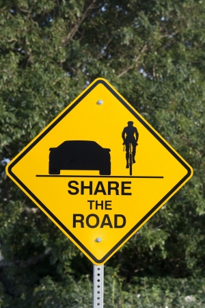 Yellow sign with text: share the road. Give bicycles more spaceの写真素材