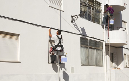 Two painters in harnasses working on a wall in Portugalのeditorial素材