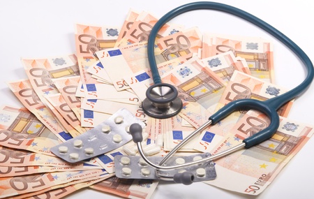 Stethoscope and pills on a big stack of eurosの写真素材