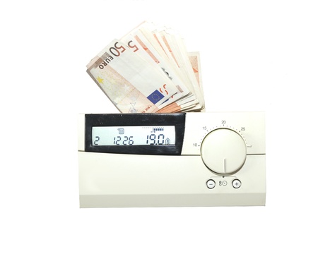 Euro bills behind the thermostat of the central heating system. Concept for the costs of energyの写真素材