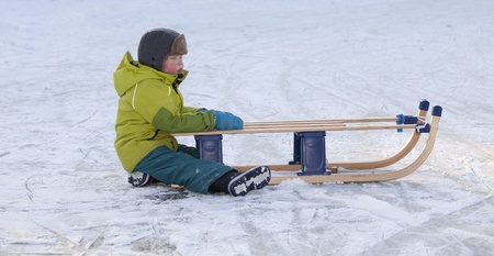 THE NETHERLANDS-FEB 4:Small tired boy sitting on ice with red cheeks holding on to his sleigh on feb 4, 2012. February is the coldest month throughout the Netherlands with an average of -0.5¡C. This february although temperatures dropped to a minus 20 ¡Cのeditorial素材