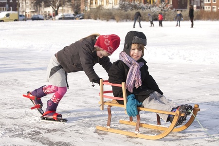 THE NETHERLANDS-FEB 4:Girl on ice skates pushes brother on sleigh on ices on feb 4, 2012. February is the coldest month throughout the Netherlands with an average of -0.5¡C. This february although temperatures dropped to a minus 20 ¡Cのeditorial素材