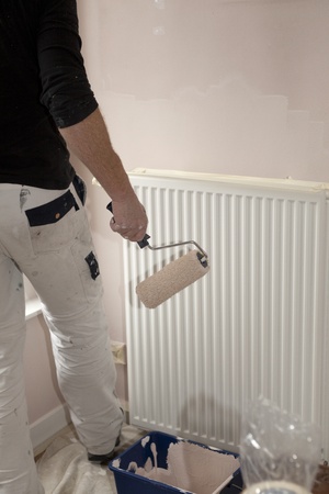 Painter with paintroll in hand in front of radiatorの写真素材