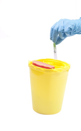 Hand in blue glove throwing away syringe in containerの写真素材