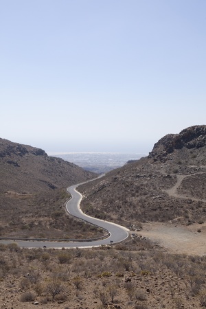 Downhill road through mountains to coastの写真素材