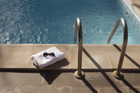Towel and sunglasses near the swimming pool