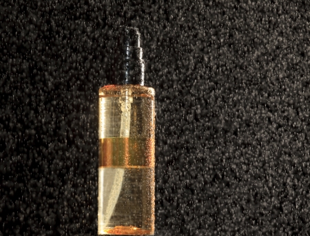 Golden colored bottle on black with waterdropsの写真素材