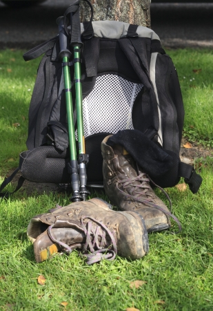 Backpack leaning against tree with hiking poles, hiking boots and socksの写真素材