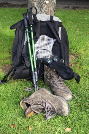 Backpack leaning against tree with hiking poles, hiking boots, binoculars and socksの写真素材