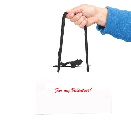 Hand in blue sweater holding white bag with black cord  and red text:For my Valentineの写真素材