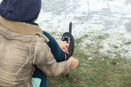 Woman with hat putting on ice skates on the grass