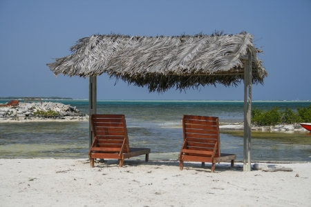 two wooden reclining chairs under a thatched roof at the caribbean ocean  in Bonaireの写真素材