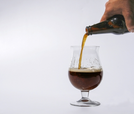 Male hand pouring dark beer in glassの写真素材