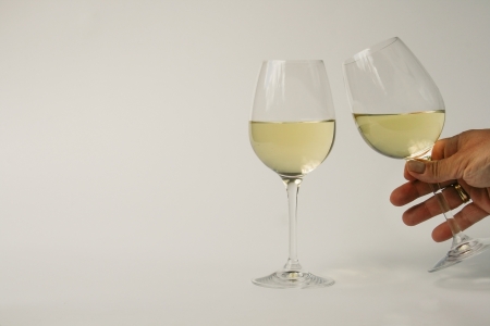 Two glasses with white wine. One glass in hand toasting the otherの写真素材