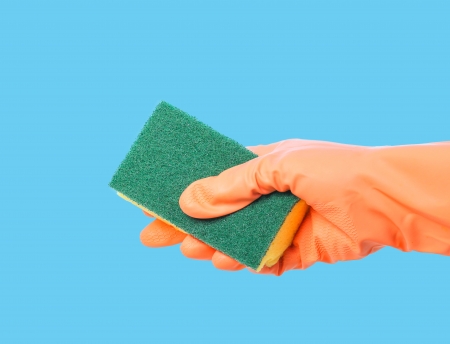 Orange gloved hand cleaning with sponge on blue backgroundの写真素材